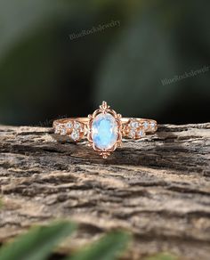 a ring with an oval blue stone surrounded by small diamonds on top of a piece of wood