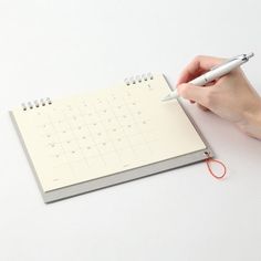 a person writing on a calendar with a pen