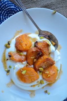 a white plate topped with food on top of a blue and white table cloth next to a spoon