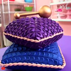 a purple and blue pillow sitting on top of a table next to a gold handle