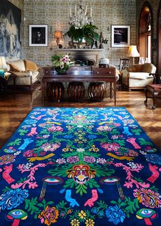 a living room filled with furniture and a blue rug on top of a hard wood floor