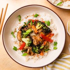 two bowls filled with rice, broccoli and chicken on top of a table