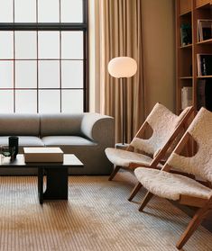 a living room filled with furniture next to a large window and bookshelf in front of it