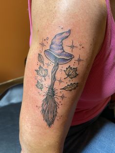 a woman with a tattoo on her arm has a wizard hat and broom in it