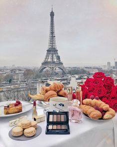 a table topped with pastries and cakes in front of the eiffel tower