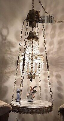 a chandelier hanging over a table with a cell phone on it and two chairs in the background