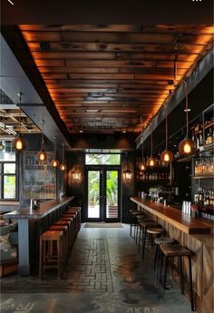 the inside of a bar with lots of stools and lights hanging from the ceiling