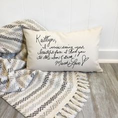 a white pillow sitting on top of a wooden floor next to a black and white blanket