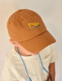 a baby wearing a brown hat with a yellow truck embroidered on it's side