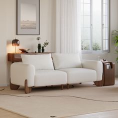 a white couch sitting on top of a rug in a living room next to a window