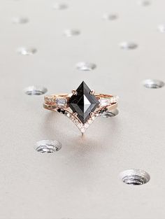 a black and white diamond ring sitting on top of a table with diamonds around it