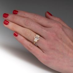 a woman's hand with red nail polish holding an engagement ring on her finger