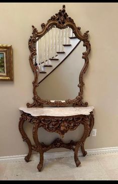 an ornate mirror and bench in front of a stair case with marble top on the floor