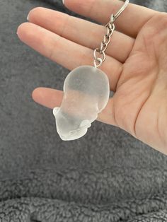 a hand holding a clear plastic object in it's left hand, with a chain attached to it