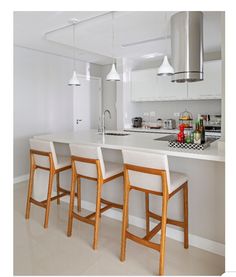 a kitchen with white counter tops and wooden chairs