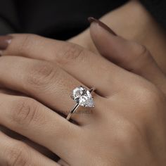 a woman's hand with a diamond ring on her left hand, showing the center stone