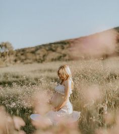 a pregnant woman standing in a field with flowers