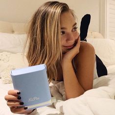 a woman laying in bed with a book