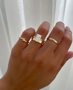 a woman's hand with two gold rings on it and one diamond in the middle