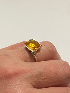 This Vintage 10k White Gold Yellow Sapphire Ring is magnificent! The ring showcases a Emerald set in a four prong setting The Sapphire stone has beautiful color. The stone measures approximately 10mm x 12mm = 6.84 carats The setting is beautiful with a unique style The ring is marked U - 10k Weight- 3.61g Size-7 Yellow Emerald Cut Topaz Ring In Fine Jewelry Style, Yellow Topaz Emerald-cut Ring In Fine Jewelry, Yellow Emerald-cut Topaz Ring Fine Jewelry, Yellow Emerald-cut Topaz Ring, Formal Yellow Solitaire Jewelry, Classic Emerald Cut Yellow Topaz Ring, Classic Yellow Topaz Ring With Emerald Cut, Classic Yellow Emerald Cut Topaz Ring, Classic Yellow Topaz Ring With Center Stone