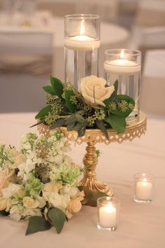 a table topped with candles and flowers on top of a white table cloth covered table