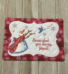 a snowman with a red scarf and hat on it's head is embroidered onto the side of a wooden surface