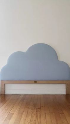 a bed with a cloud shaped headboard on top of it in a room that has hardwood floors