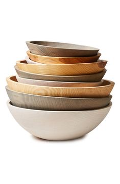 four bowls stacked on top of each other in different colors and sizes, with one bowl made out of wood