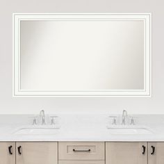 a bathroom vanity with two sinks and a large mirror above it, in front of a white wall