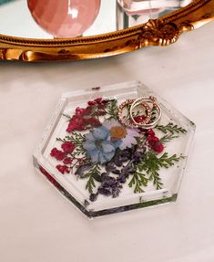 a flower arrangement is placed in front of a mirror on top of a table with other items