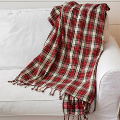 a red and white plaid blanket sitting on top of a couch next to a pillow