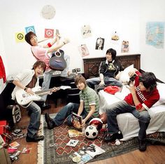 group of young people sitting on a bed with guitars