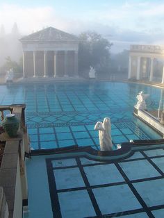 two statues sitting on the edge of a swimming pool