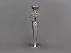 a tall metal candle holder sitting on top of a white table next to a gray wall