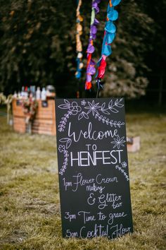 a chalkboard sign that says welcome to henfest hanging from a string in the grass