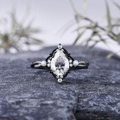 a black and white diamond ring sitting on top of a rock