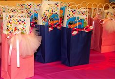 colorful bags are lined up on a pink and blue tablecloth with polka dotty bows