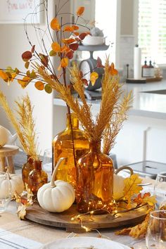 the table is set for thanksgiving dinner with pumpkins and gourds in vases