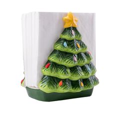 a ceramic christmas tree sitting on top of a white napkin dispenser in front of a white background