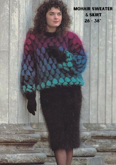 a woman wearing a multicolored sweater and skirt standing in front of a column