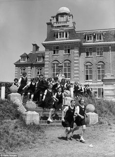 black and white photograph of girls posing in front of an old building