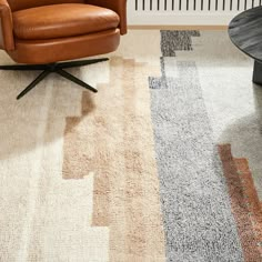 a brown chair sitting on top of a rug next to a wooden table and wall