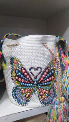 a white purse with multicolored beads and a butterfly on it