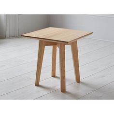 a small wooden table sitting on top of a white floor next to a wall and window