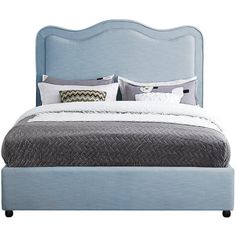 a bed with blue upholstered headboard and pillows