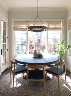 a dining room table with four chairs and a potted plant in the window sill