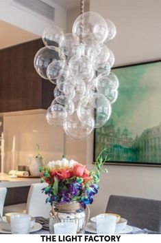 a dining room table with plates and cups on it next to a vase filled with flowers