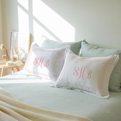 two monogrammed pillows sit on top of a bed