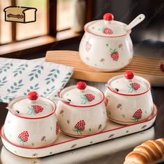 four pieces of ceramic tea set sitting on a tray next to some croissants