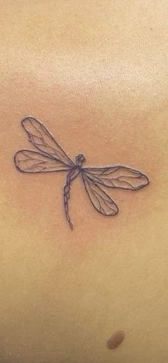 a woman's stomach with a dragonfly tattoo on it